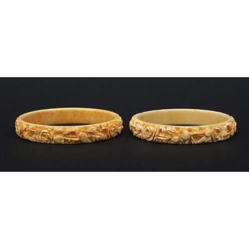 629 - Two oriental Chinese ivory bangles both carved with flowers, each 7.5cm diameter