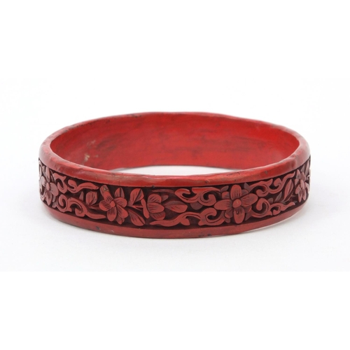 651 - Oriental Chinese cinnabar lacquer bangle carved with flowers, 7cm diameter