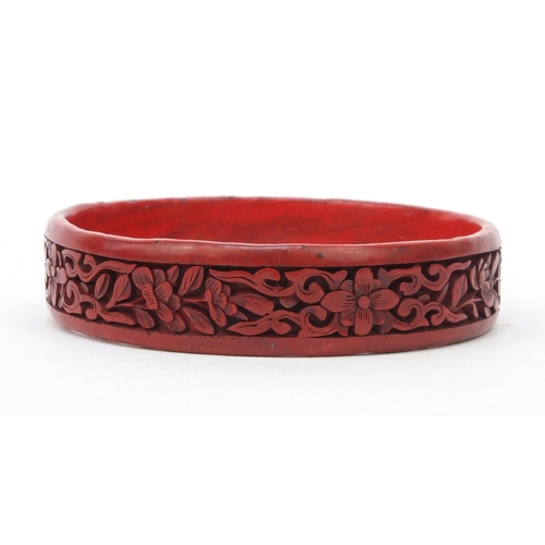 651 - Oriental Chinese cinnabar lacquer bangle carved with flowers, 7cm diameter