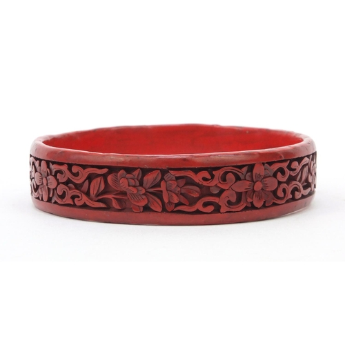 651 - Oriental Chinese cinnabar lacquer bangle carved with flowers, 7cm diameter