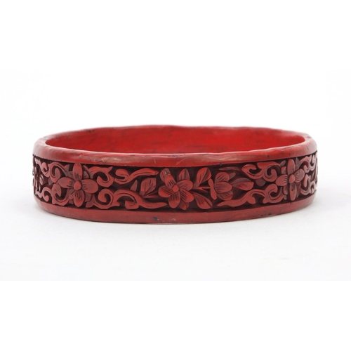 651 - Oriental Chinese cinnabar lacquer bangle carved with flowers, 7cm diameter