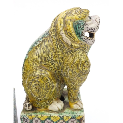 558 - Two oriental Chinese stoneware lion dogs hand painted with floral bases, each 26cm high