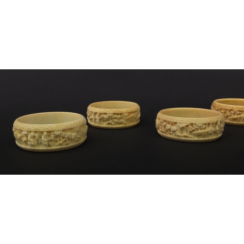 627 - Group of seven oriental Chinese Canton ivory napkin rings carved with figures, pagodas and trees, ea... 