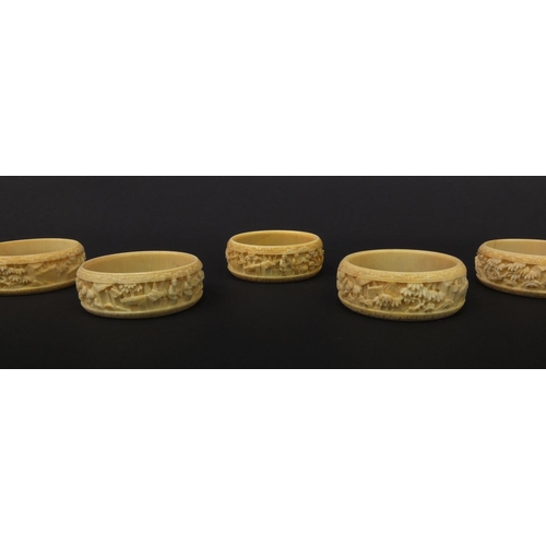 627 - Group of seven oriental Chinese Canton ivory napkin rings carved with figures, pagodas and trees, ea... 