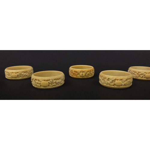 627 - Group of seven oriental Chinese Canton ivory napkin rings carved with figures, pagodas and trees, ea... 