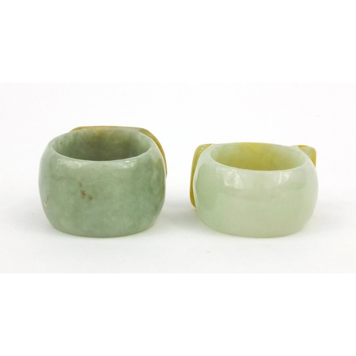 639 - Two oriental Chinese jade thumb rings - one carved with a lion, the other with bats, 3.5cm diameter