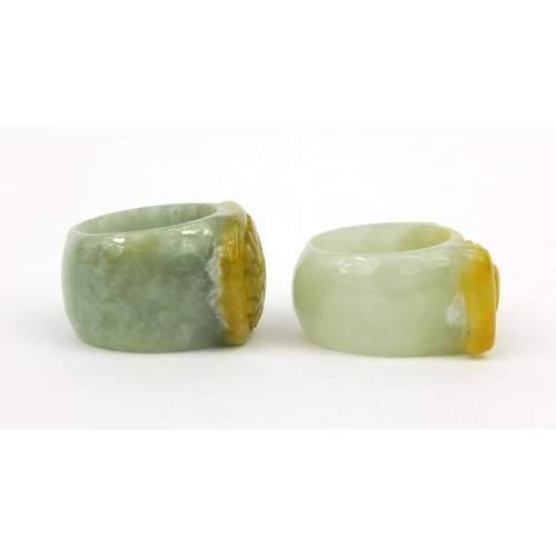 639 - Two oriental Chinese jade thumb rings - one carved with a lion, the other with bats, 3.5cm diameter