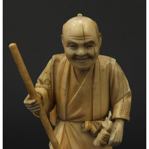 605 - Oriental Japanese ivory okimono of a gentleman with a stick and a basket, 15.5cm high