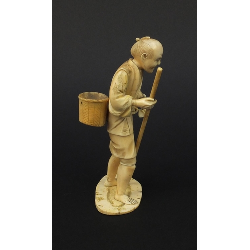 605 - Oriental Japanese ivory okimono of a gentleman with a stick and a basket, 15.5cm high