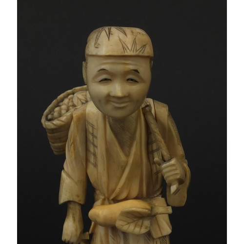 603 - Oriental Japanese ivory okimono of a fruit seller raised on a bone base, 15cm high