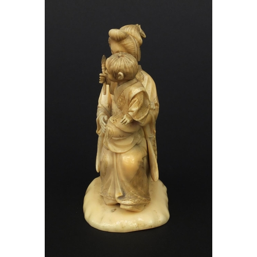 607 - Oriental Japanese ivory okimono of a mother and child holding a flaming torch, red character mark to... 