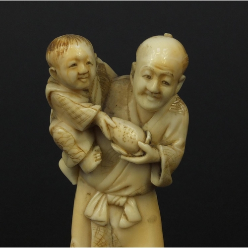 608 - Oriental Japanese ivory okimono of a father and young child holding fruit, 10cm high