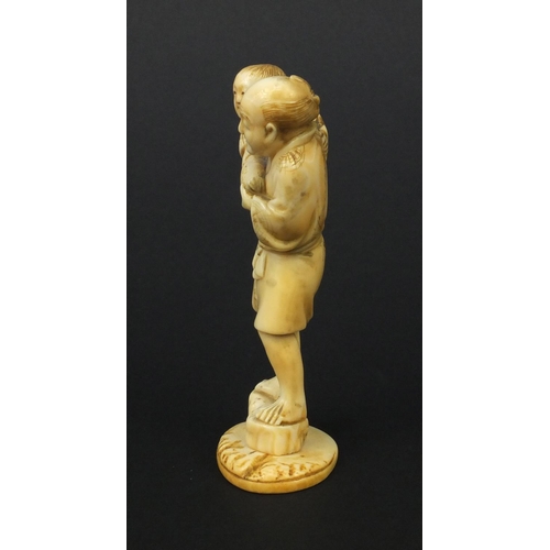 608 - Oriental Japanese ivory okimono of a father and young child holding fruit, 10cm high