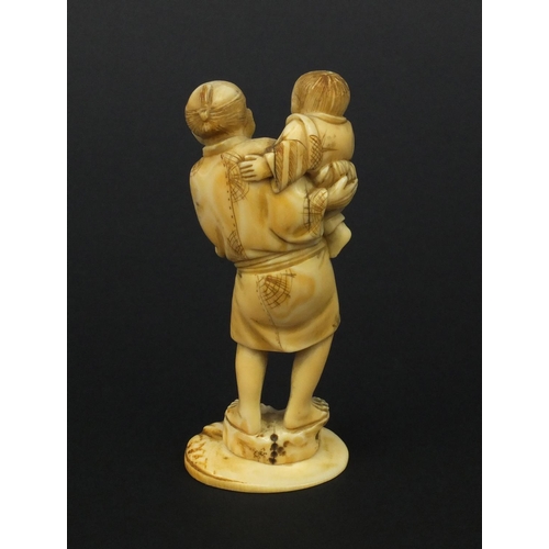 608 - Oriental Japanese ivory okimono of a father and young child holding fruit, 10cm high