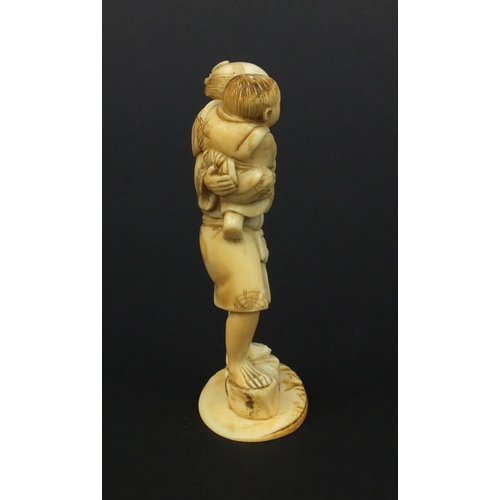 608 - Oriental Japanese ivory okimono of a father and young child holding fruit, 10cm high