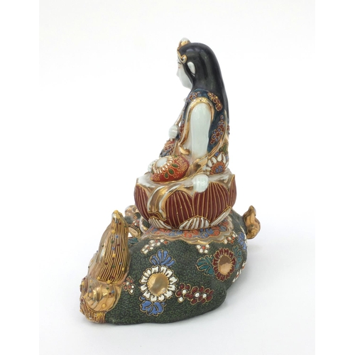 594 - Oriental Japanese satsuma pottery figure of a girl seated on a Buddhistic lion, 21cm high