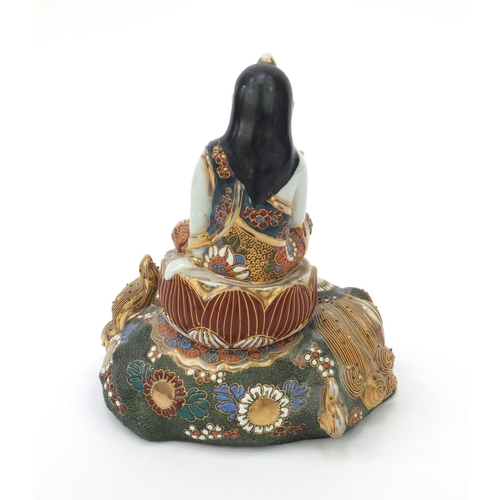 594 - Oriental Japanese satsuma pottery figure of a girl seated on a Buddhistic lion, 21cm high