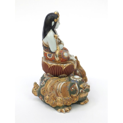 594 - Oriental Japanese satsuma pottery figure of a girl seated on a Buddhistic lion, 21cm high