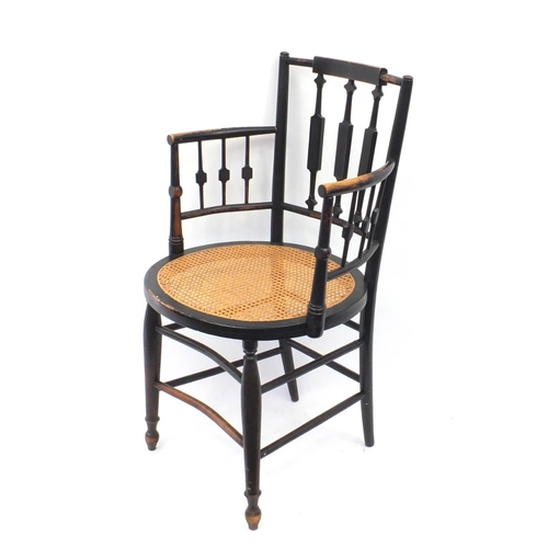 2025 - Arts and craft E Godwin style ebonised elbow chair with cane seat 88cm tall