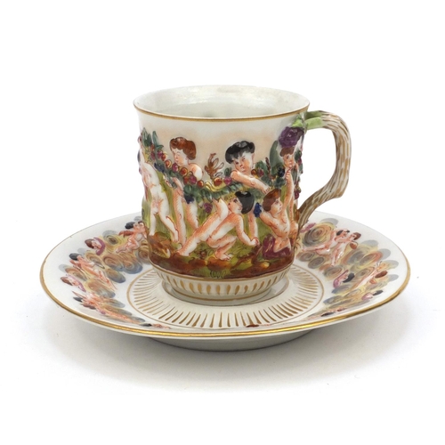593 - Naples hand painted cup and saucer decorated with relief with continuous band of figures carrying a ... 