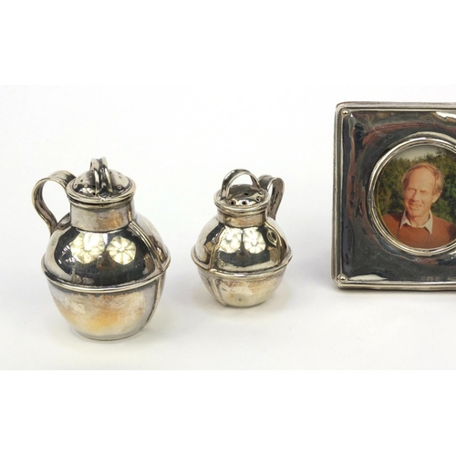 784 - Silver items comprising a milk jug with embossed floral decoration, two miniature Jersey cream cans ... 