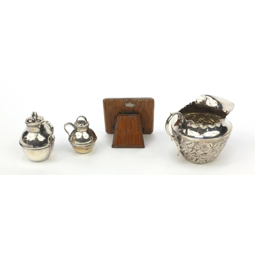 784 - Silver items comprising a milk jug with embossed floral decoration, two miniature Jersey cream cans ... 