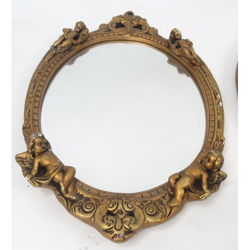 75 - Two ornate oval gilt framed mirrors, one with Putti decoration, the larger approximately 64cm x 41cm