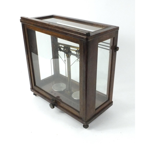 263 - Thomson. Skinner & Hamilton balance scales in a glazed oak case, 44cm high x 44cm wide, 20cm deep