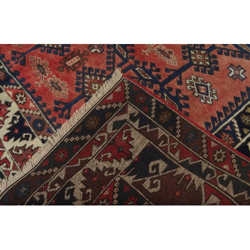 87 - Red ground geometric patterned carpet, approximately 275cm x 195cm