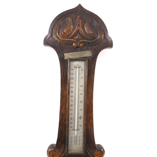 313 - Carved oak aneroid barometer with a presentation plaque, 84cm high