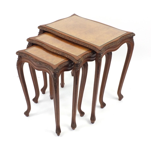 2021 - French style nest of three carved Burr Walnut occasional tables with glass tops, tallest 62cm high