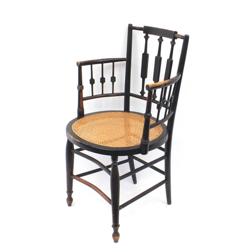 152 - Arts and craft E Godwin style ebonised elbow chair with cane seat 88cm tall