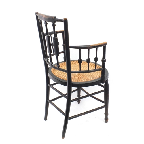 152 - Arts and craft E Godwin style ebonised elbow chair with cane seat 88cm tall