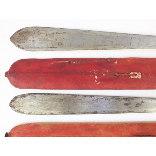 601 - Two Kenyan panga knifes with red sheaths, the longest 56cm long