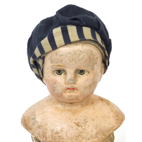 441 - Straw filled doll wearing a hat with composite head and limbs, 28cm high