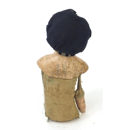 441 - Straw filled doll wearing a hat with composite head and limbs, 28cm high