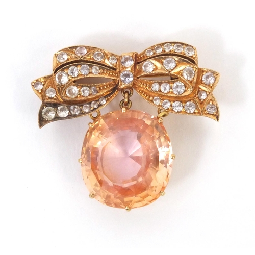 823 - Unmarked gold bow brooch set with a padparadscha sapphire and white sapphire stones, 3.2cm long, app... 