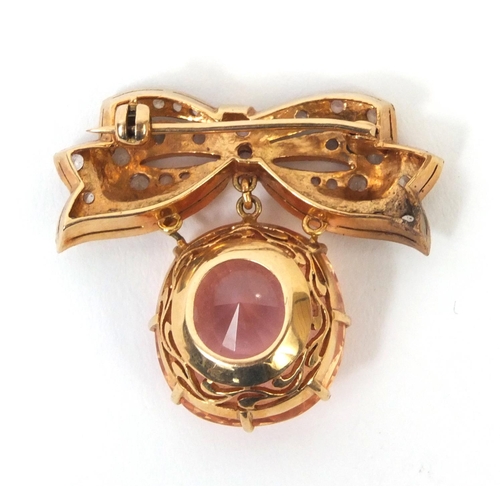 823 - Unmarked gold bow brooch set with a padparadscha sapphire and white sapphire stones, 3.2cm long, app... 