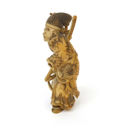 503 - Japanese finely carved ivory okimono of a samari warrior holding a katana and stick, signature to th... 