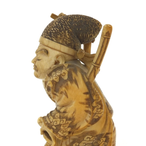 503 - Japanese finely carved ivory okimono of a samari warrior holding a katana and stick, signature to th... 