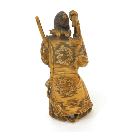 503 - Japanese finely carved ivory okimono of a samari warrior holding a katana and stick, signature to th... 