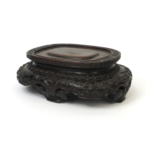 547 - Chinese hardwood stand carved with mythical faces, 9cm high x 26cm wide x 17,5cm deep