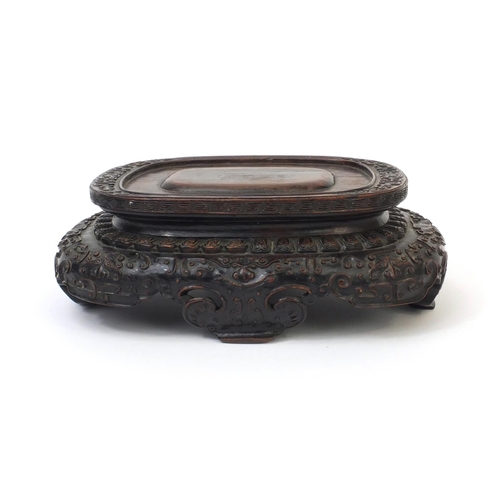 547 - Chinese hardwood stand carved with mythical faces, 9cm high x 26cm wide x 17,5cm deep