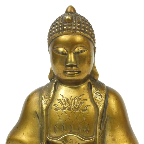 567 - Chinese brass Buddha raised on a hardwood stand, the Buddha with incised decoration and character ma... 