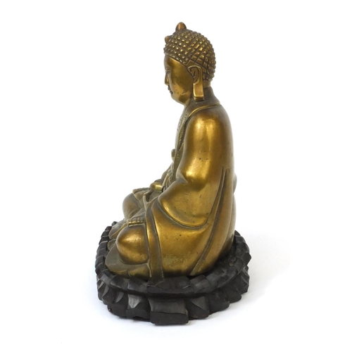 567 - Chinese brass Buddha raised on a hardwood stand, the Buddha with incised decoration and character ma... 