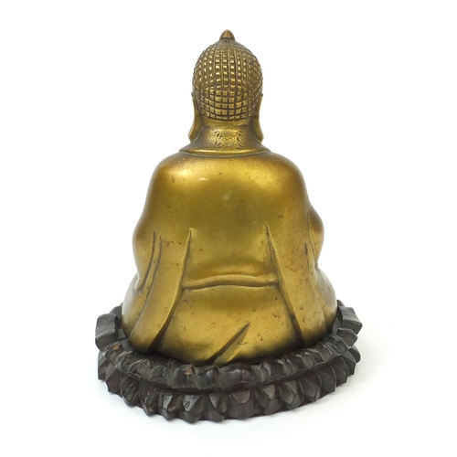 567 - Chinese brass Buddha raised on a hardwood stand, the Buddha with incised decoration and character ma... 