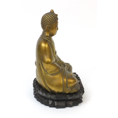 567 - Chinese brass Buddha raised on a hardwood stand, the Buddha with incised decoration and character ma... 