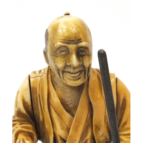 506 - Japanese carved ivory okimono of an elder holding a stick, character marks to the base, 20cm high