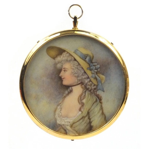 26 - Circular portrait miniature of a lady wearing a wide brimmed hat onto ivory, housed in a gold colour... 