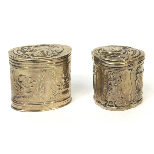 774 - Two unmarked silver trinkets with hinged lids, embossed with figures and putti, the larger 3.5cm hig... 